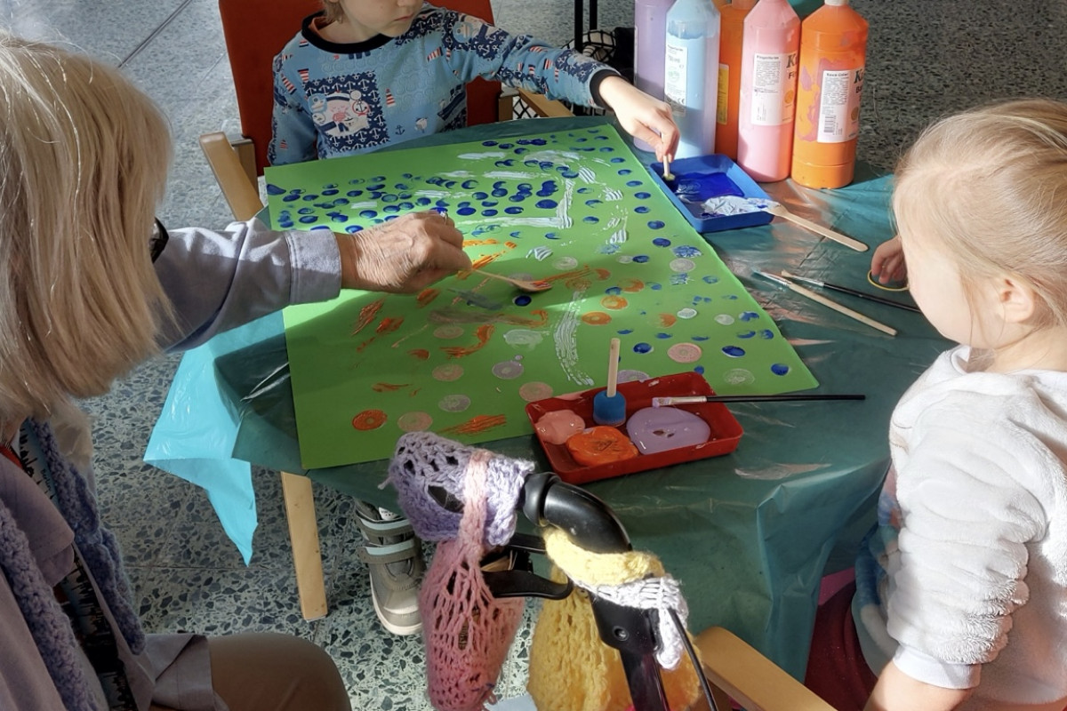 Kinder spielen und basteln mit Seniorin