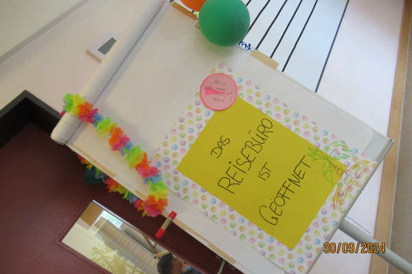 Schild mit der Aufschrift: Das Reisebüro ist geöffnet!