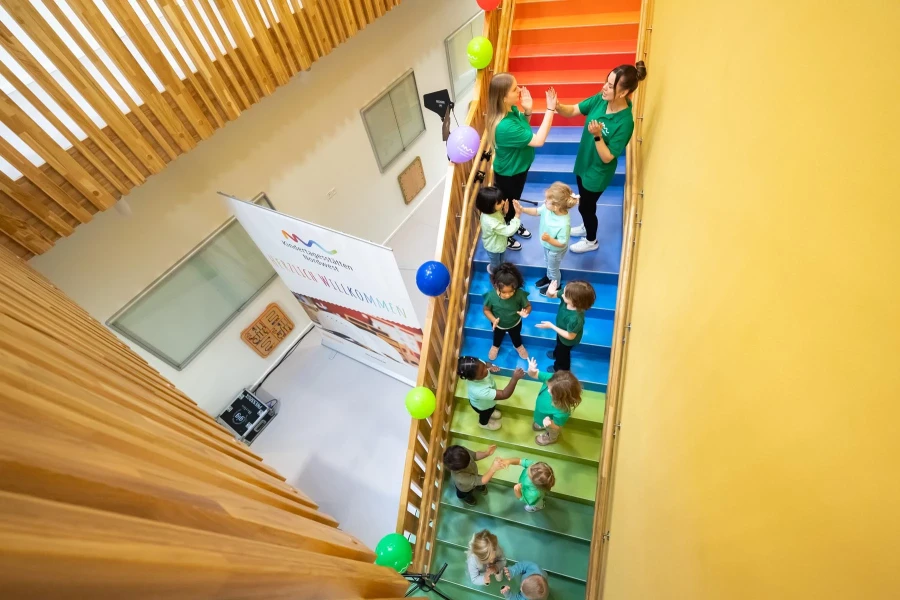 Kita-Kinder und Team führen eine Aufführung auf der zentralen Treppe auf 