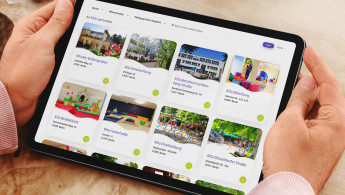 Person hält ein Tablet mit einer Übersicht der Kitas in der Hand