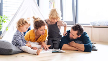 Eltern lesen mit ihren zwei Kindern ein Bilderbuch