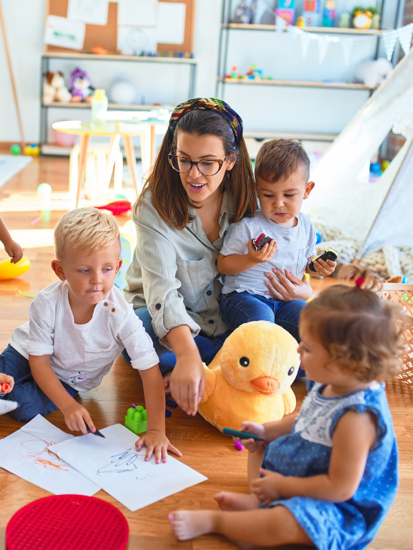 Erzieherin spielt mit Kindern und hilft ihnen freundlich