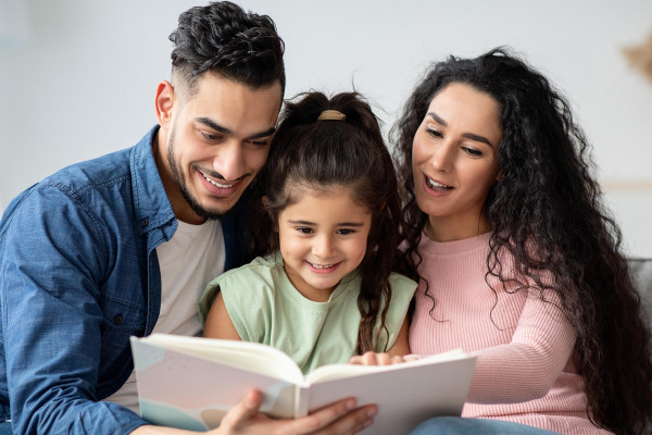 Junge Familie bringt ihrer Tochter spielerisch das Lesen bei