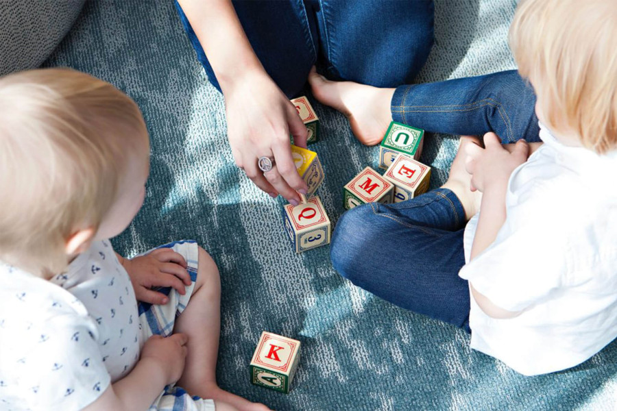 Erzieherin lehrt zwei Kindern das Sprechen mit Buchstabenwürfeln