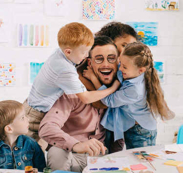 Sympathischer Erzieher wird von glücklichen Kindern herzlich empfangen
