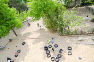 Kita Amendstraße Sandspielplatz mit Autoreifen und spielenden Kindern aus Vogelperspektive