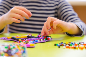 Kita Buddelkiste Kind spielt mit Perlen