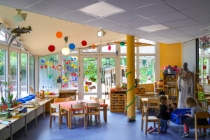 Heller Gruppenraum mit spielenden Kindern