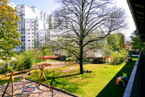 Blick vom Balkon auf den Spielplatz und den grünen Innenhof der Kita Tornower Weg