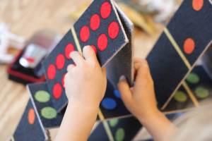 Kinderhände bauen Kartenhaus aus Dominosteinen in der Kita Warburgzeile