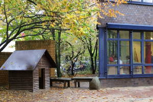 Innenhof mit Bänken und begehbarem Holzhaus im Hof der Kita Warburgzeile