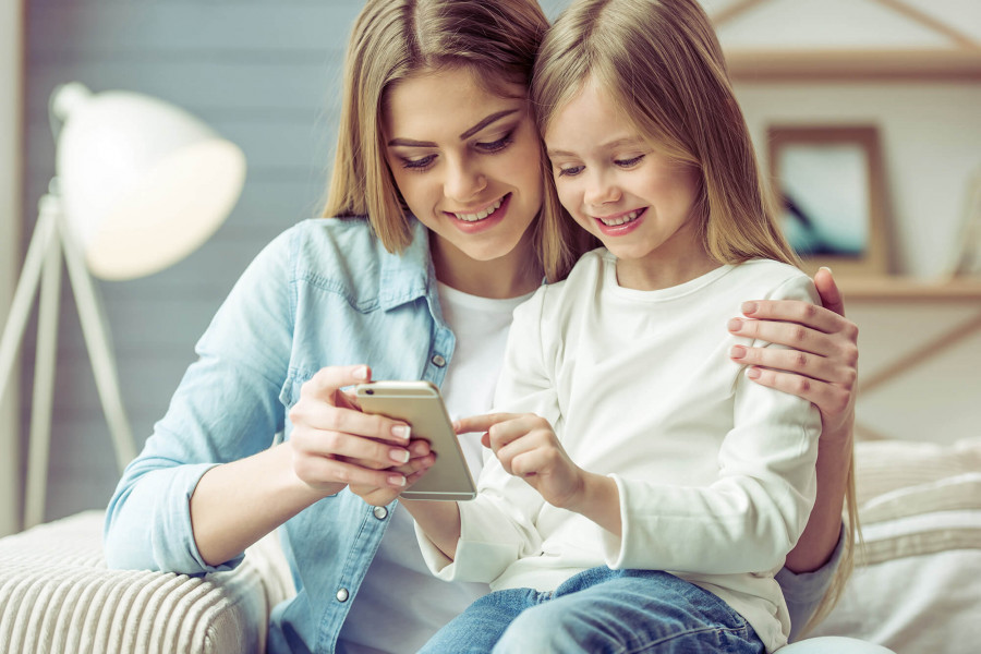 Ein Mädchen schaut zusammen mit ihrer Mutter auf ein Smartphone